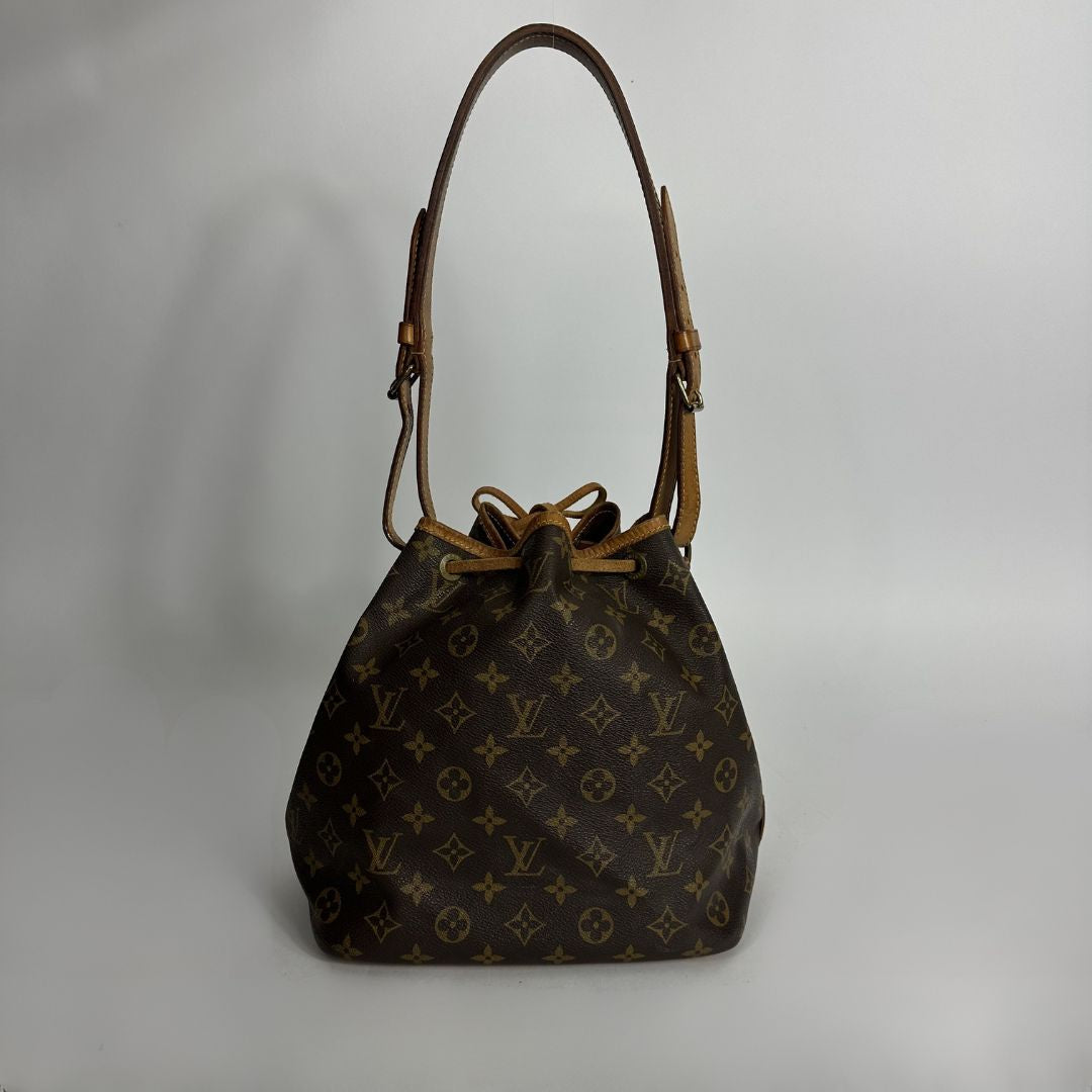 Louis Vuitton monogram canvas shoulder bag with a brown leather strap and drawstring closure, photographed against a neutral light gray background.