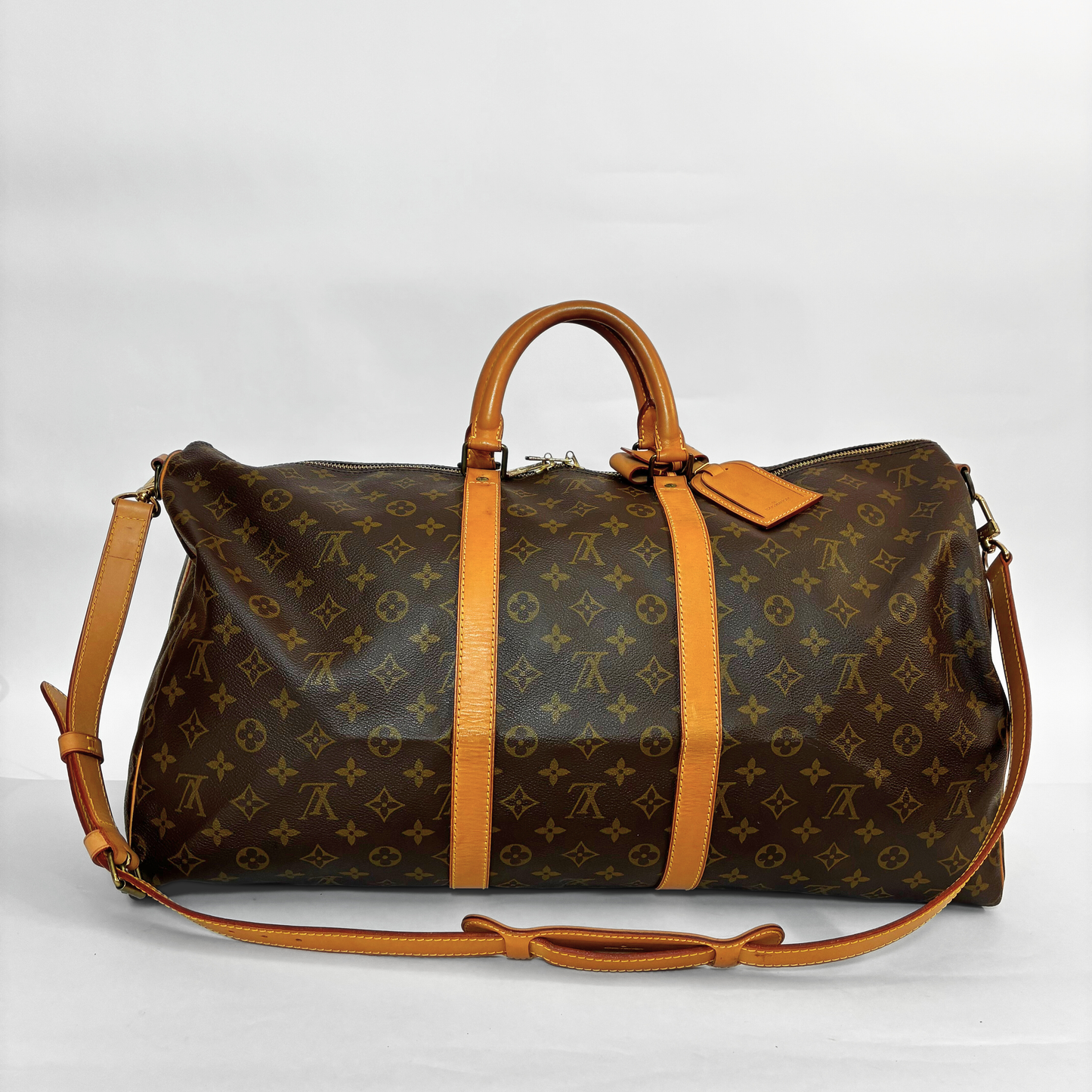 Louis Vuitton monogram travel bag with brown leather straps on a white background