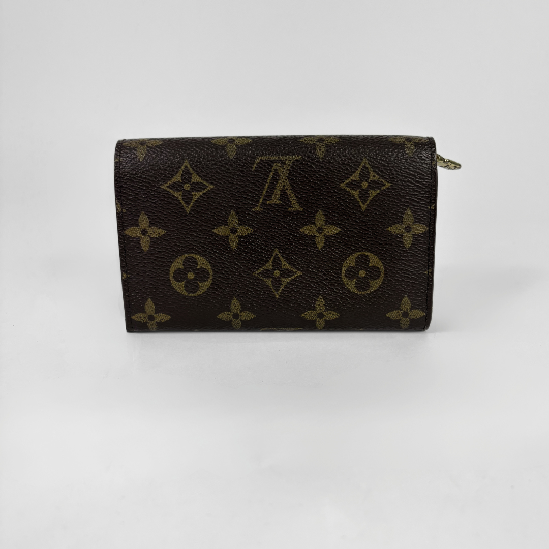 A Louis Vuitton monogram canvas zip-around wallet in dark brown with tan monogram motifs, shown on a light gray background.