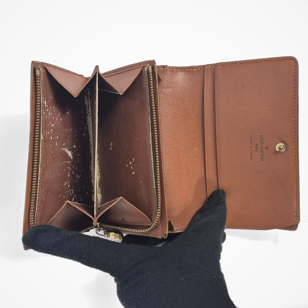 Brown leather wallet held by a gloved hand on a white background