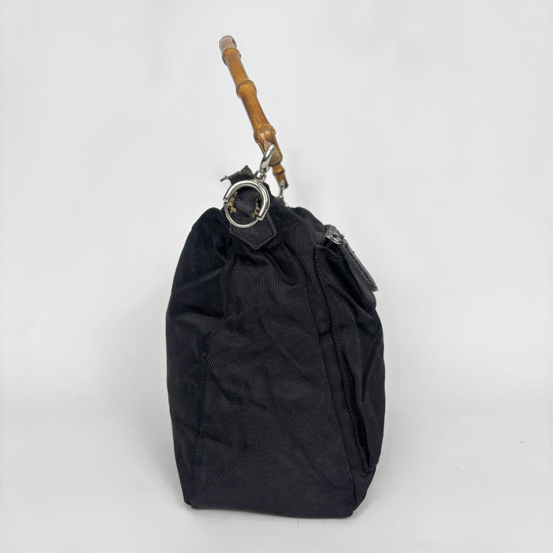 Black handbag with a bamboo handle on a white background