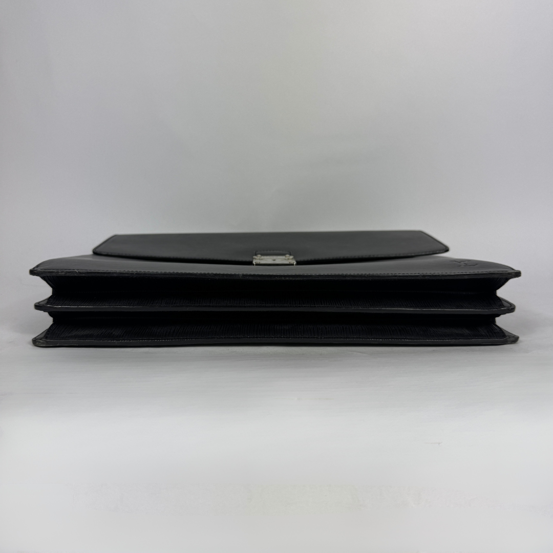 A black leather clutch bag with a silver-tone metal clasp, shown from the side on a light gray background.
