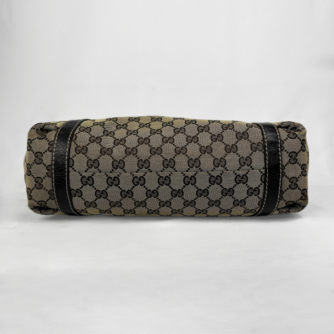 A cylindrical canvas bag or sleeve featuring the classic brown and beige GG monogram pattern, accented with black leather trim on a light gray background.