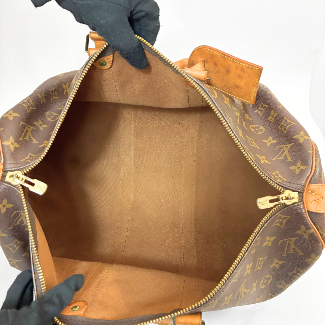 Brown LV duffel bag with monogram canvas and tan leather straps on a white background