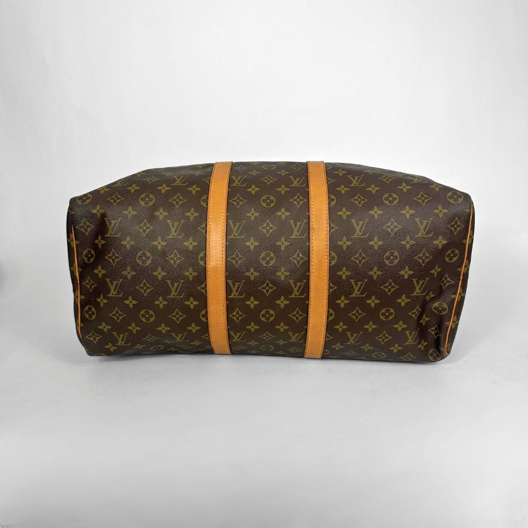 Brown monogram duffel bag with tan leather handles on a white background