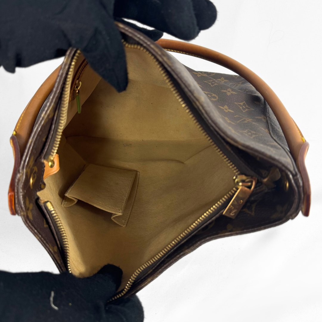A Louis Vuitton monogram handbag shown open, held by hands wearing black gloves against a plain white background. The bag features the classic brown monogram canvas, tan leather trim, and gold-tone hardware.