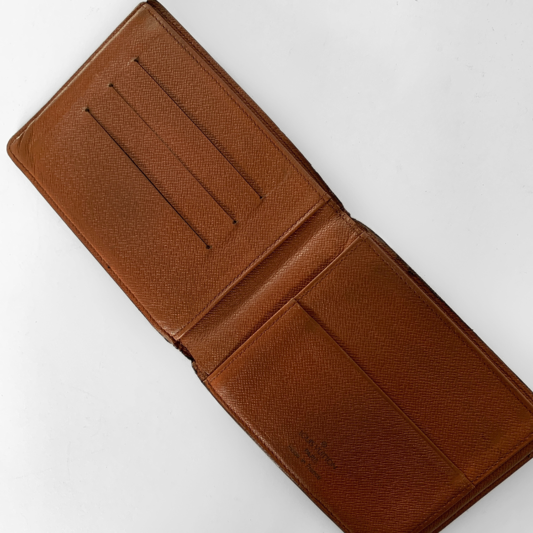An open brown leather wallet with multiple card slots and a front pocket, photographed on a plain light background.