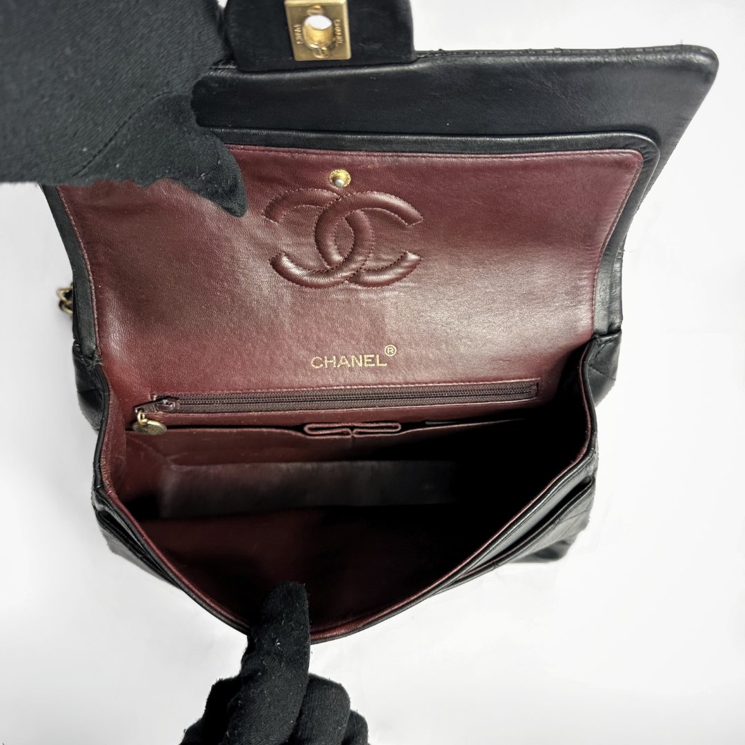 Chanel handbag with brown interior and gold logo on a white background