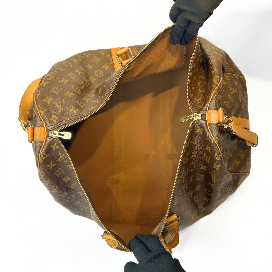 Brown Louis Vuitton bag with monogram pattern held by gloved hands on a white background