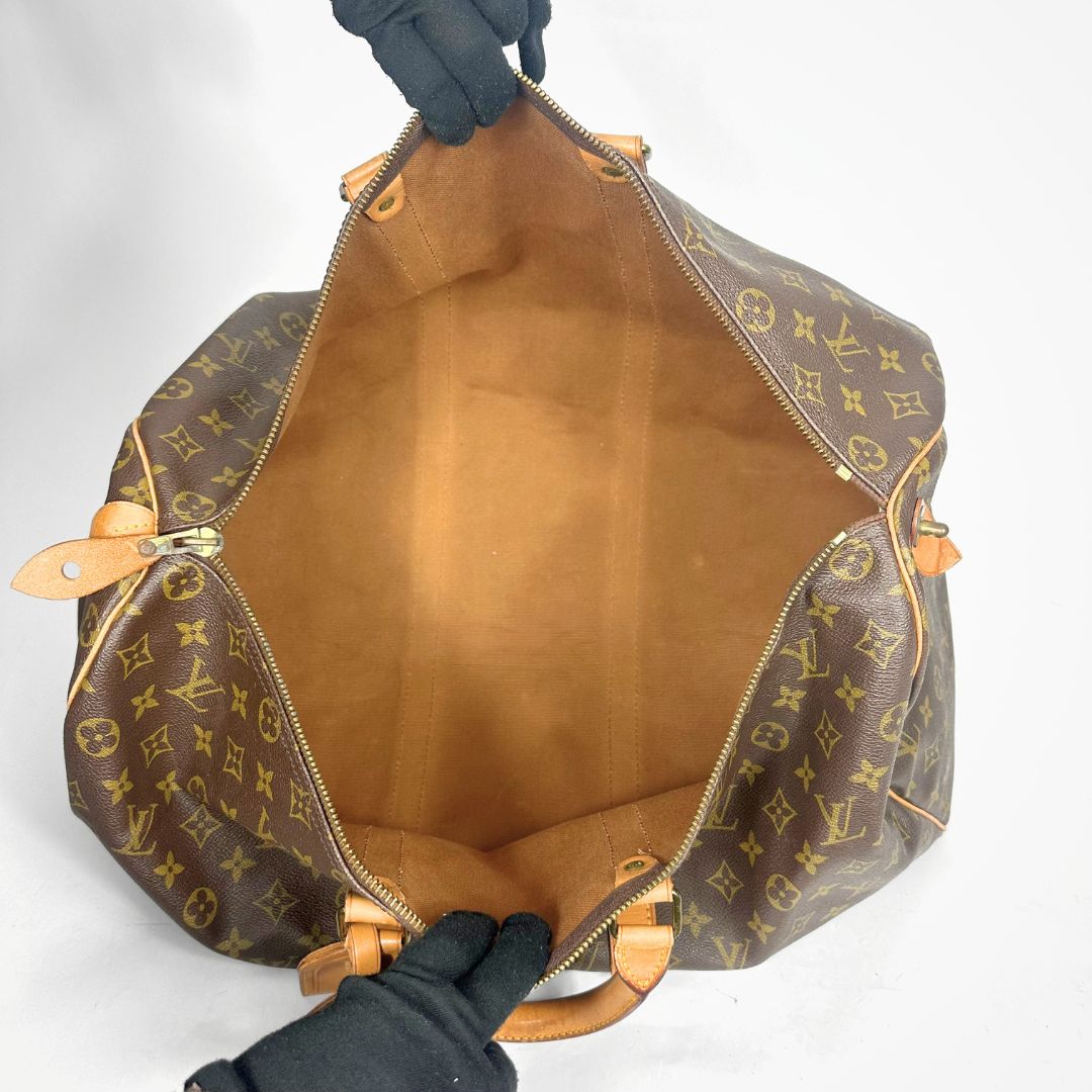 Brown monogram duffel bag with tan leather handles on a white background