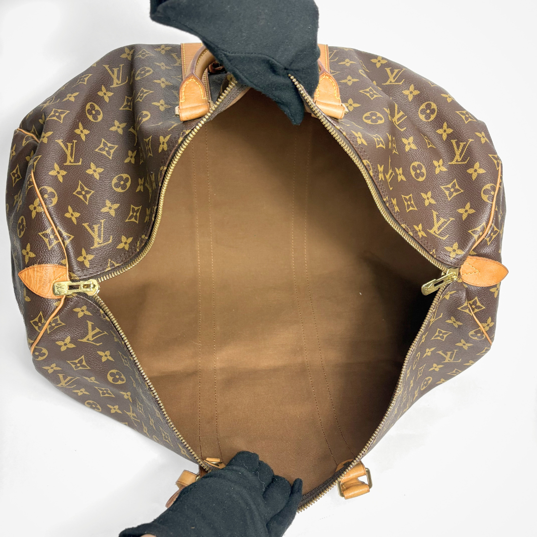 Brown monogrammed duffel bag with gold accents on a white background