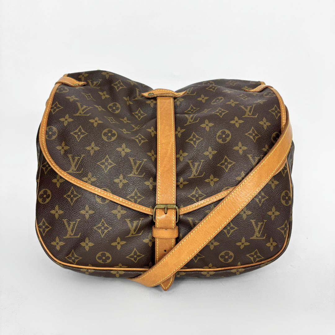 Brown monogram handbag with tan leather strap on a white background