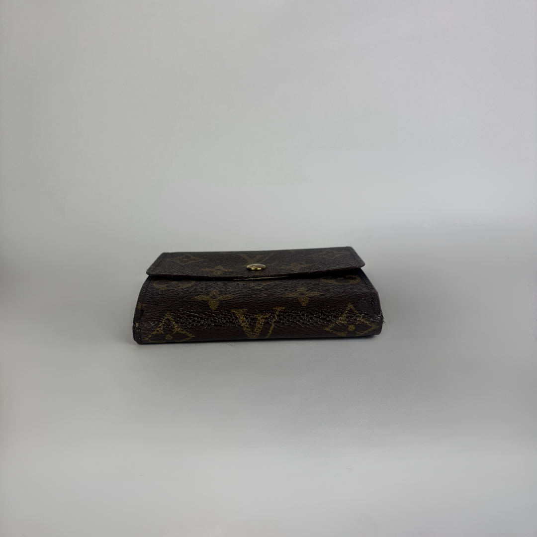 A dark brown Louis Vuitton monogram clutch wallet with a gold-tone snap button closure, set against a plain light gray background.