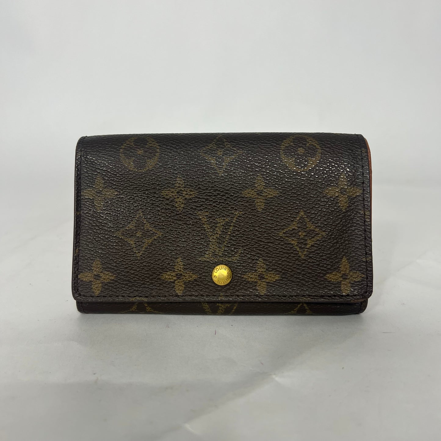 Brown wallet with gold monogram pattern on a white background